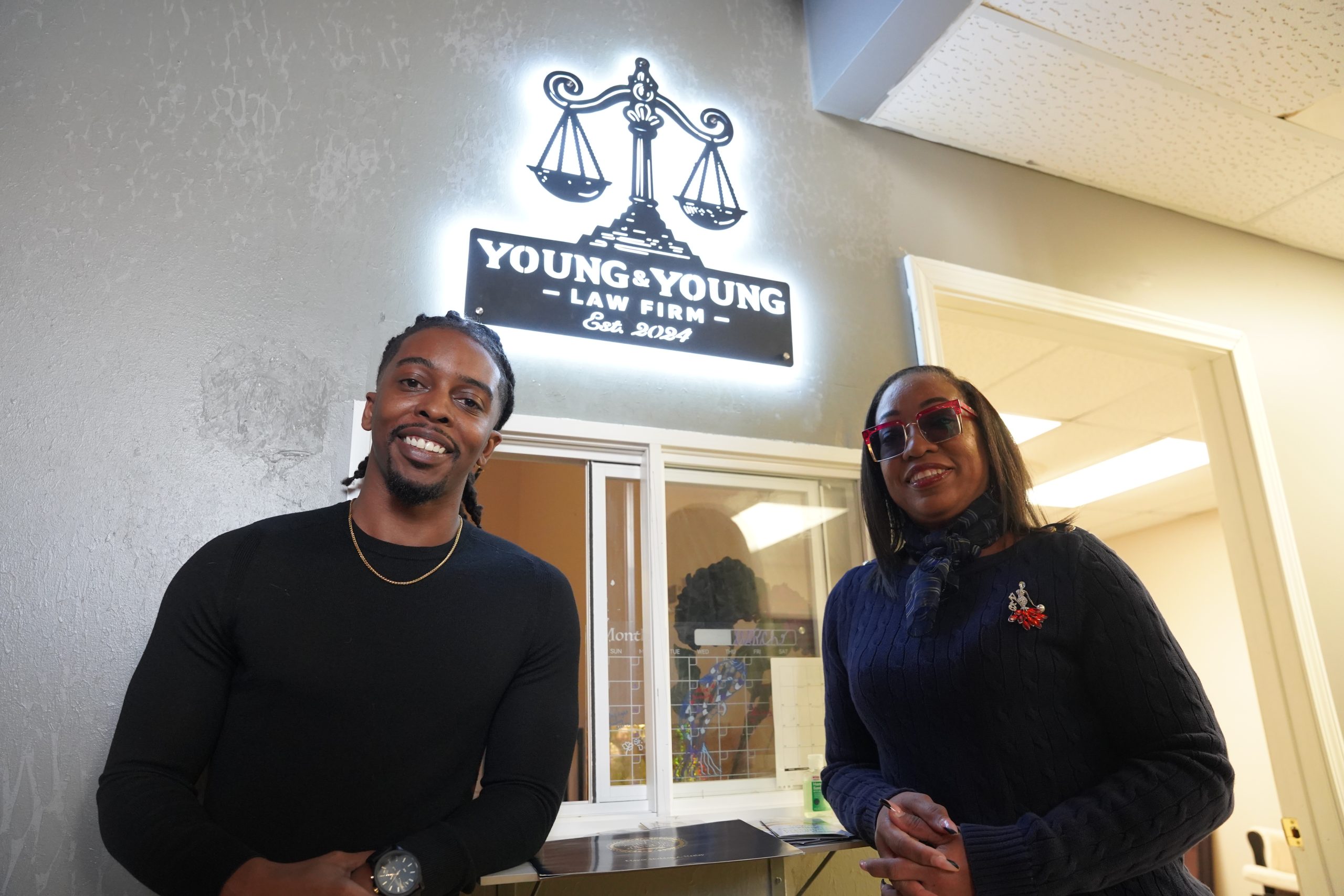 Trachelle and Curtis Young stand in front of the drive-thru legal services window at their newly opened law firm, Young & Young Law Firm, on February 21, 2025, in Flint Township, Michigan. (Joshua Johnson | Flint Beat)